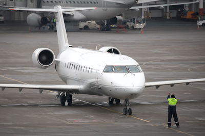 Plane on apron of the airport. airport traffic controller ground crew gives commands to an airplane.