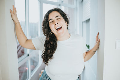 Portrait of young woman standing against wall