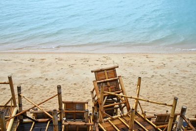 Stack of chairs against waters edge at beach