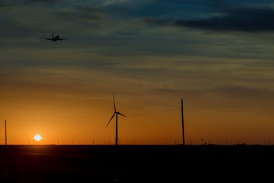 Silhouette cranes against sky during sunset