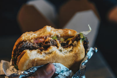 Cropped image of person holding hamburger outdoors