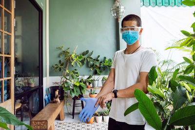 Young man standing against potted plants