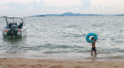 Rear view of man at beach against sky