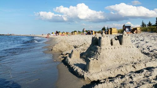 People on beach against sky with sand castle 
