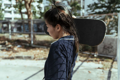 Side view of woman carrying skateboard