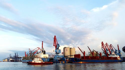 Cranes at commercial dock against sky