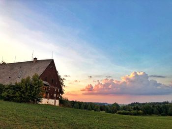 House on field against sky during sunset