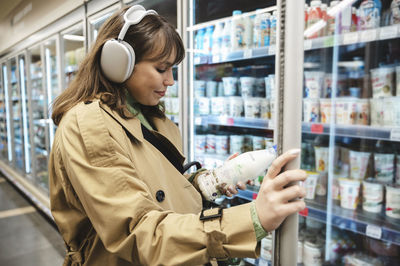 Young woman reading product description on milk bottle at supermarket