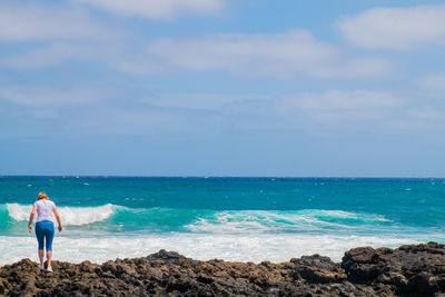 Rear view of man looking at sea against sky