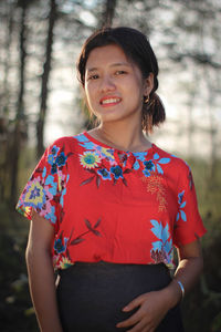 Portrait of smiling woman standing against tree