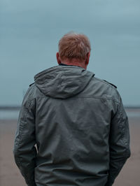 Rear view of man standing against sea against sky