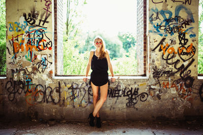 Full length of woman standing on graffiti wall