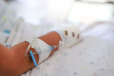 Low section of woman with iv drip on bed