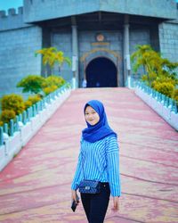 Portrait of woman standing against built structure