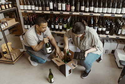 Male and female business owners removing bottles from box at wine store