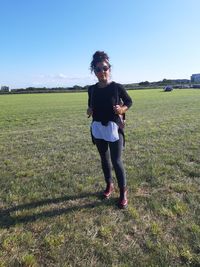 Full length of smiling young woman on field