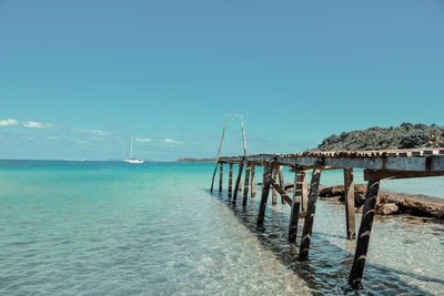 Pier over sea against clear blue sky