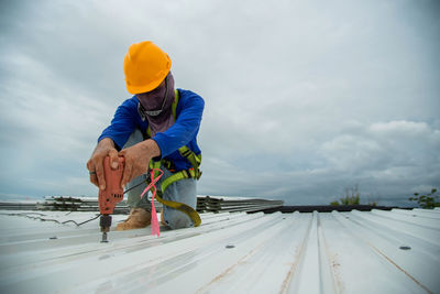 Asian construction workers are installing metal roofing sheets for industrial roof installations.