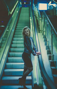 Low angle view of young woman standing on escalator