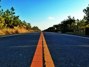 Surface level of empty road against blue sky