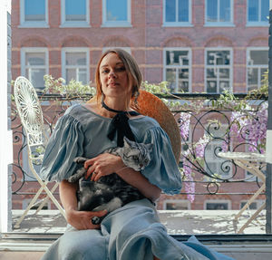 Portrait of woman sitting against building