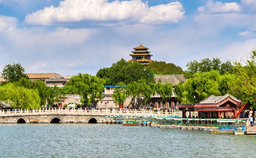 Buildings by river against sky