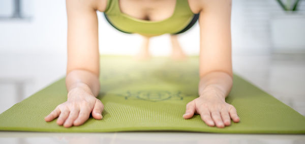 Women do yoga planks on the green yoga mat to meditate and exercise in the home.