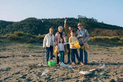 Portrait of happy family cleaning beach