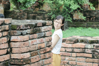 Portrait of woman standing against brick wall