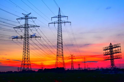 Low angle view of electricity pylon against sky during sunset