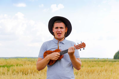 Guitar player. young beautiful caucasian man playing ukulele outside. handsome hipster guy plays 