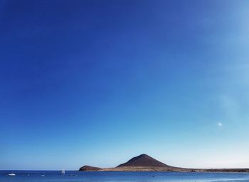 Panoramic view of sea against clear blue sky