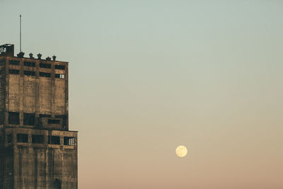 Full moon beside old grain elevator.