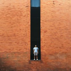 Man standing on retaining wall of red brick wall