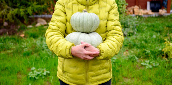 A happy woman holds two grey pumpkins from her garden plot. healthy, eco-friendly food concept
