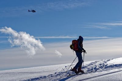 Man flying over snowcapped mountain against sky