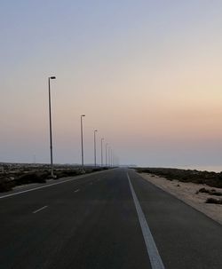 Empty road against sky during sunset