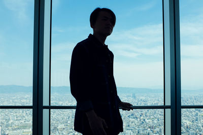 Man standing by sea against sky seen through window