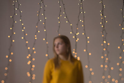 Teenage girl standing against illuminated lights