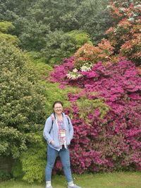 Full length portrait of woman standing by flowering plant