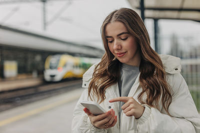 Woman using smart phone at rail station