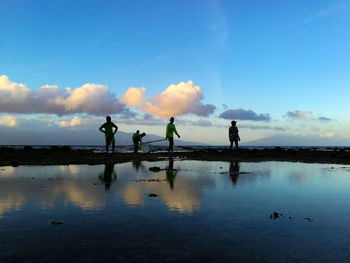 People on lake against blue sky