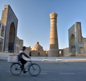 Blurred motion of man riding bicycle on street building in city