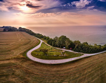 Scenic view of road by sea against sky during sunset