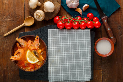 Tom yam soup with shrimps and coconut milk on the table on a checkered napkin near the ingredients 