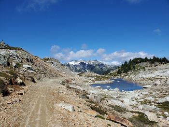 Scenic view of road by mountains against blue sky