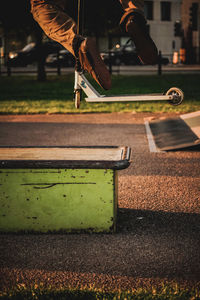 Low section of man riding push scooter at playground