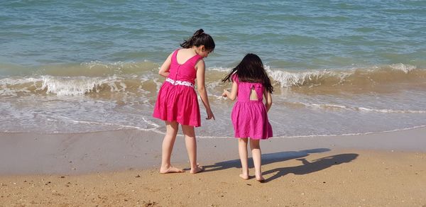 Rear view full length of girls standing on shore at beach