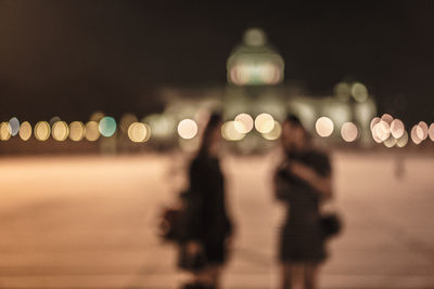 Defocused image of illuminated city against sky at night