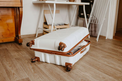 Open white suitcase on the floor at home